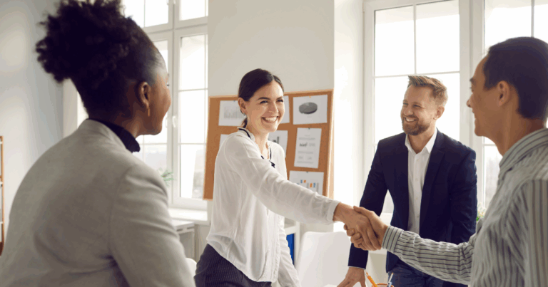 Business partners smiling and shaking hands after a meeting about how to franchise my business.
