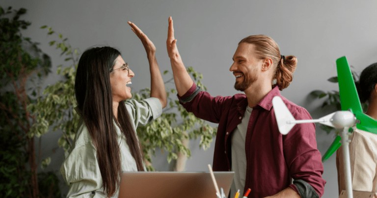 Two franchise executives celebrating success with a high-five while reviewing business performance metrics in a modern office