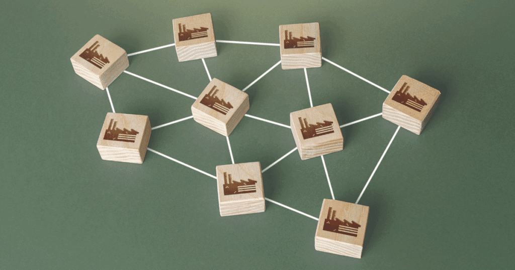 Interconnected wooden blocks with factory icons representing a franchise supply chain management network and distribution system.
