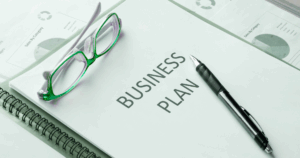 Close-up of a printed business plan with green glasses and a pen, representing the foundation of scalable franchise plans.